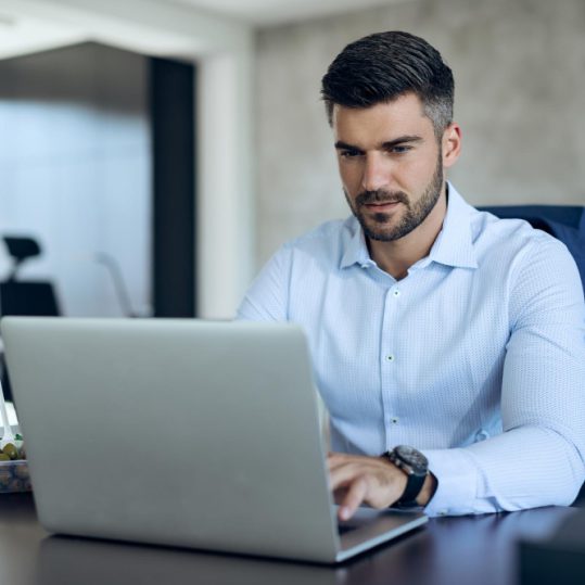 empresario-masculino-que-usa-computadora-mientras-trabaja-oficina